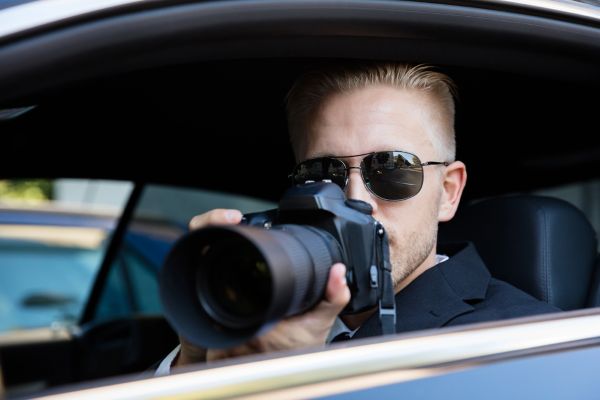 Image of a man with sunglasses doing surveillance with a camera