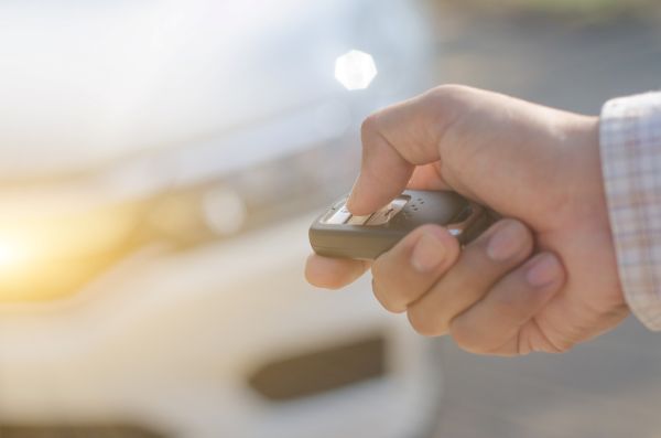 image of hand holding key fob out towards a car