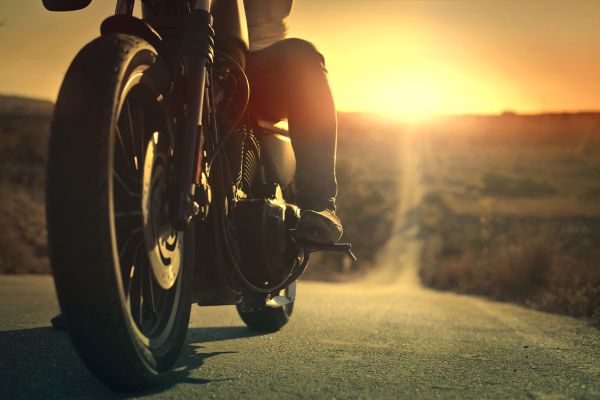 Image of a man riding motorcycle at sunset