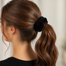 A woman shown from the back wearing a black velvet scrunchie with a covert audio recorder in a ponytail.